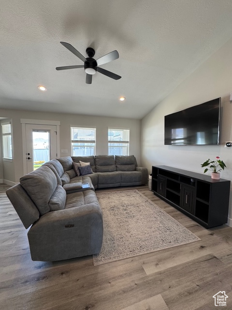 Living room with ceiling fan, light wood finished floors, recessed lighting, a textured ceiling, and vaulted ceiling
