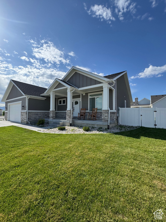 Craftsman-style house featuring board and batten siding, stone siding, a porch, an attached garage, and driveway