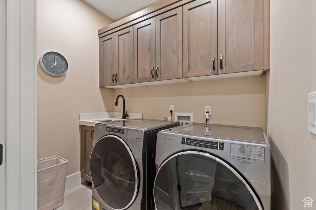Laundry room with washer and clothes dryer, cabinet space, and light tile patterned flooring