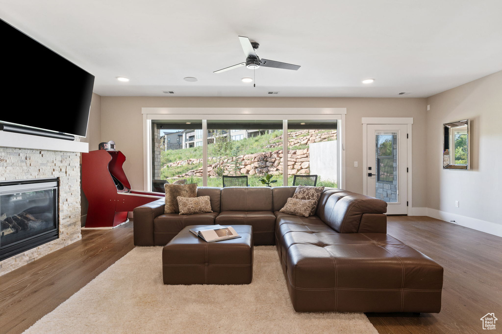 Living area with wood finished floors, a stone fireplace, a ceiling fan, and recessed lighting
