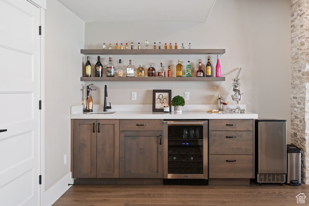 Indoor wet bar with beverage cooler and dark wood-style floors