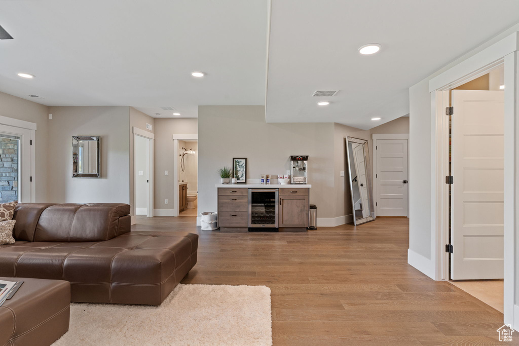 Living room featuring beverage cooler, light wood-style flooring, recessed lighting, and stairs