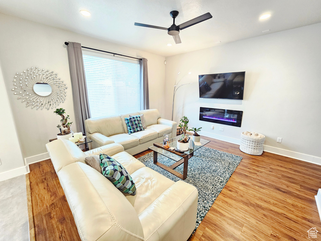 Living area featuring ceiling fan, wood finished floors, recessed lighting, and a glass covered fireplace