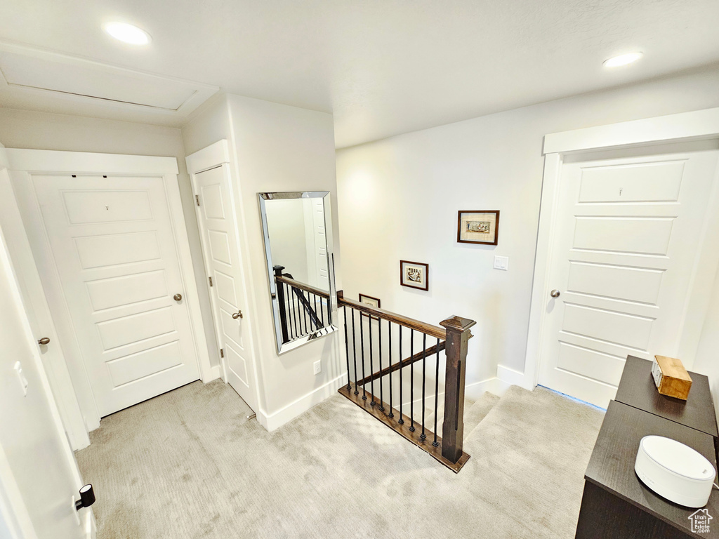 Hallway with an upstairs landing, light colored carpet, and recessed lighting