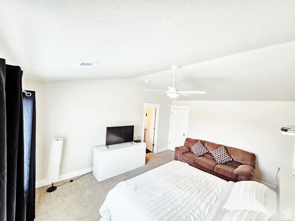 Bedroom featuring light colored carpet, vaulted ceiling, and a ceiling fan