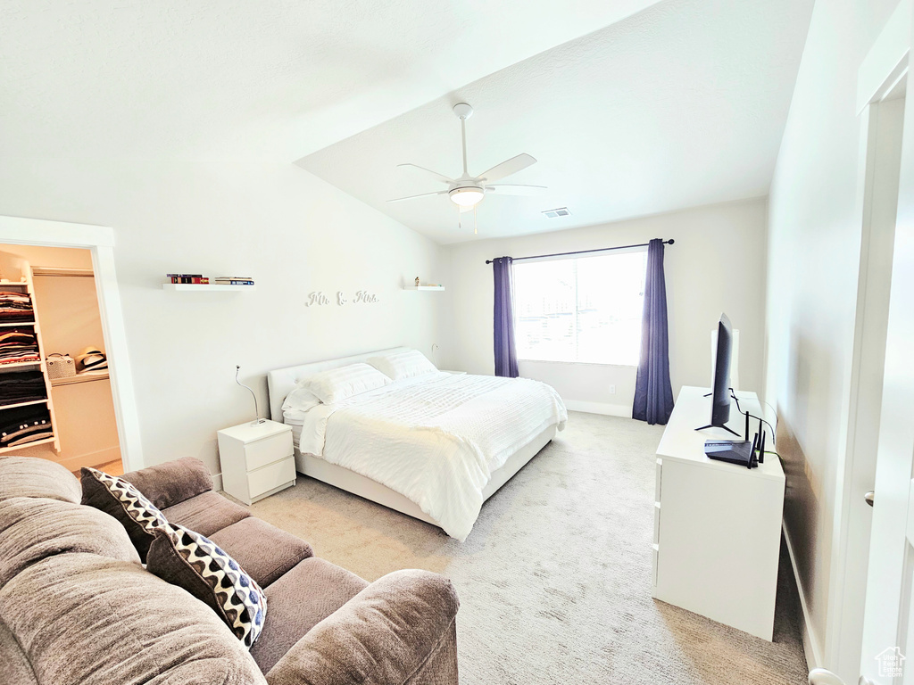 Bedroom with light colored carpet, lofted ceiling, ceiling fan, and a spacious closet