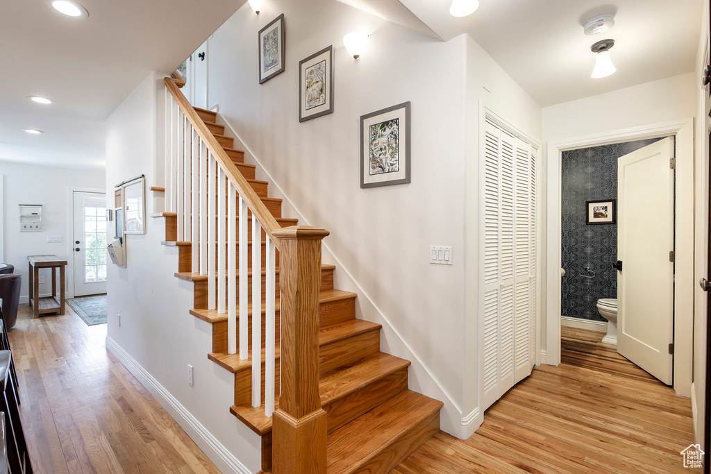 Stairs with wood finished floors and recessed lighting
