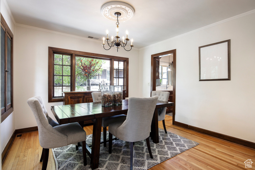 Dining room with a chandelier, light wood-style floors, and crown molding