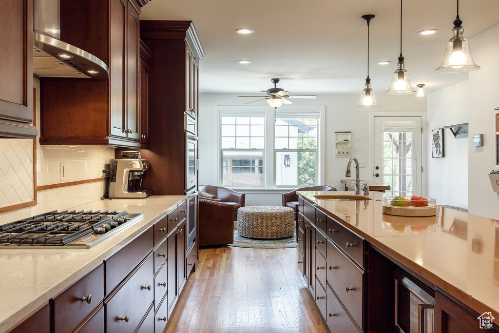 Kitchen with stainless steel gas cooktop, light wood-style flooring, ceiling fan, recessed lighting, and decorative light fixtures