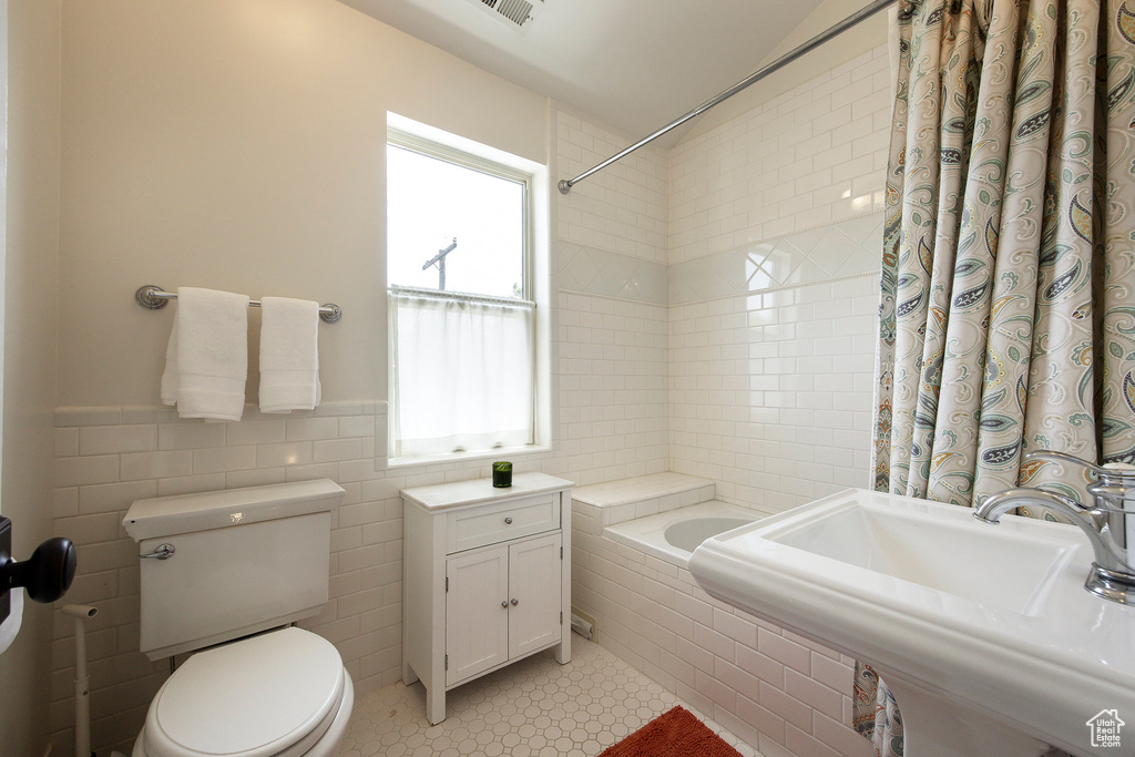 Bathroom with tile walls, shower / tub combo, and tile patterned floors