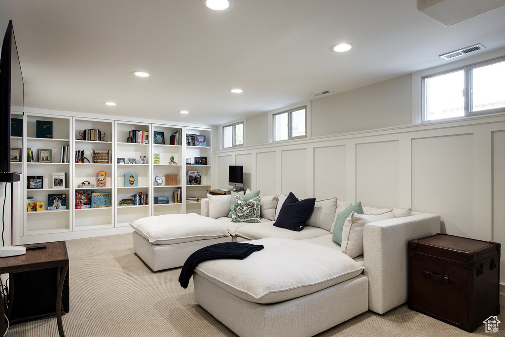 Living room featuring a decorative wall, recessed lighting, wainscoting, and light colored carpet