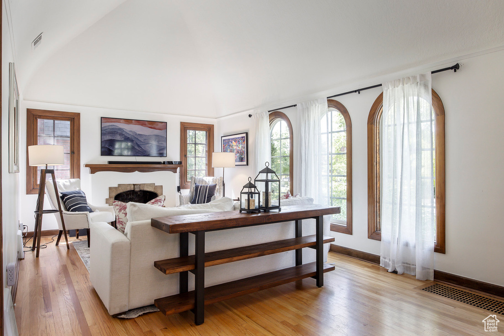 Living area with a fireplace, light wood-style flooring, and lofted ceiling