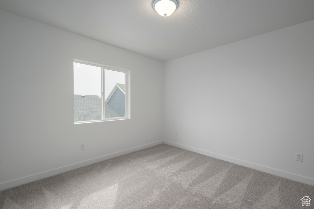 Unfurnished room featuring light carpet and baseboards