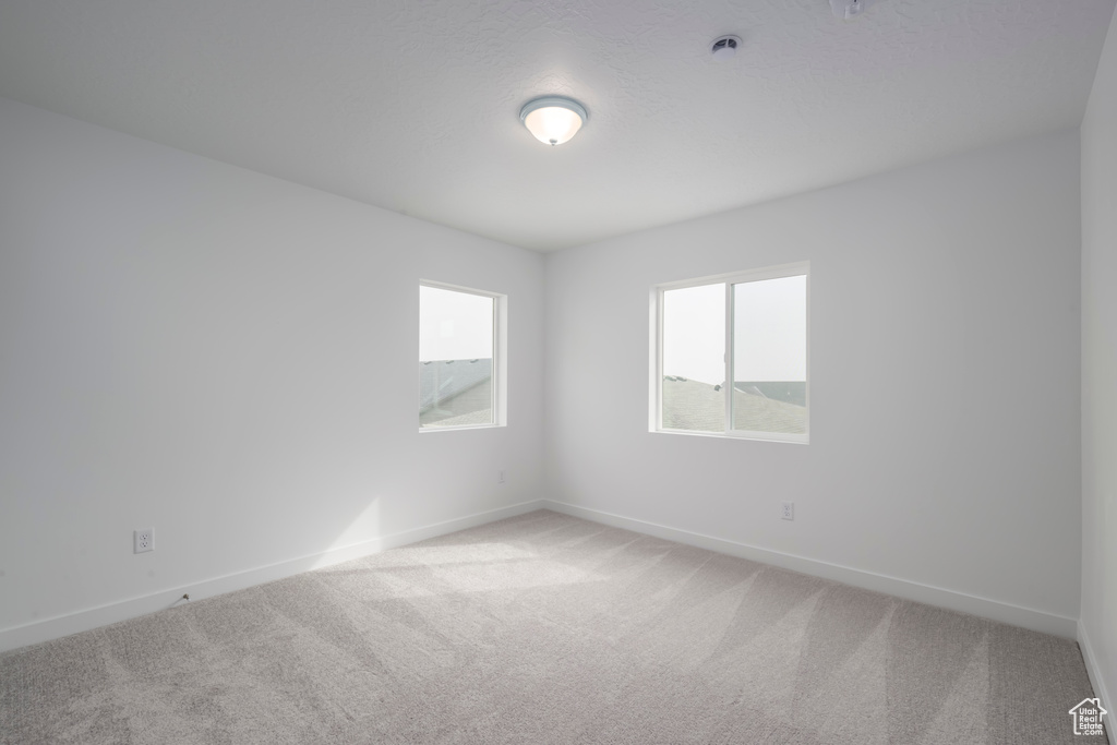 Unfurnished room featuring light carpet and baseboards