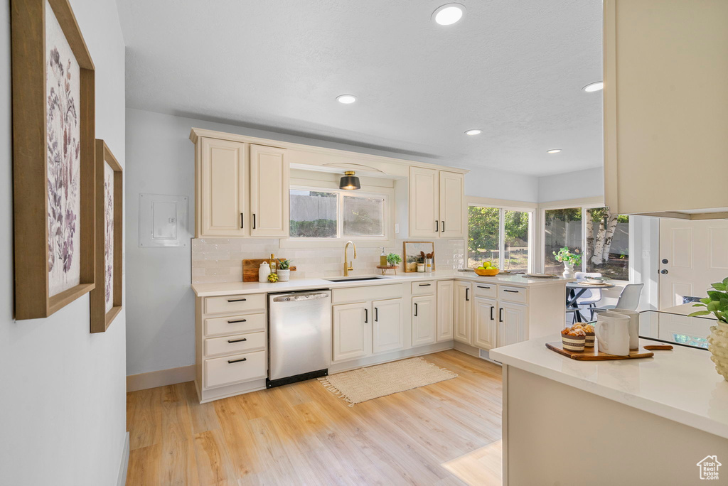 Kitchen with stainless steel dishwasher, backsplash, light countertops, light wood-style flooring, and recessed lighting