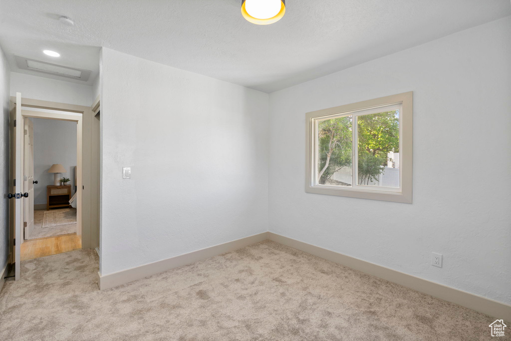 Carpeted spare room featuring attic access and a smoke detector