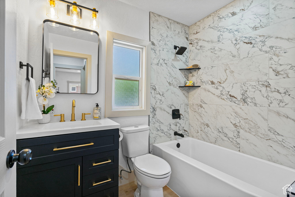 Bathroom featuring vanity, shower / bath combination, and wood finished floors
