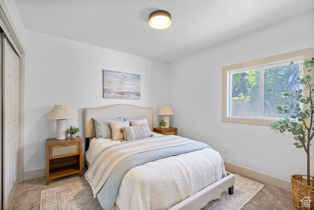 Bedroom with light carpet and a closet