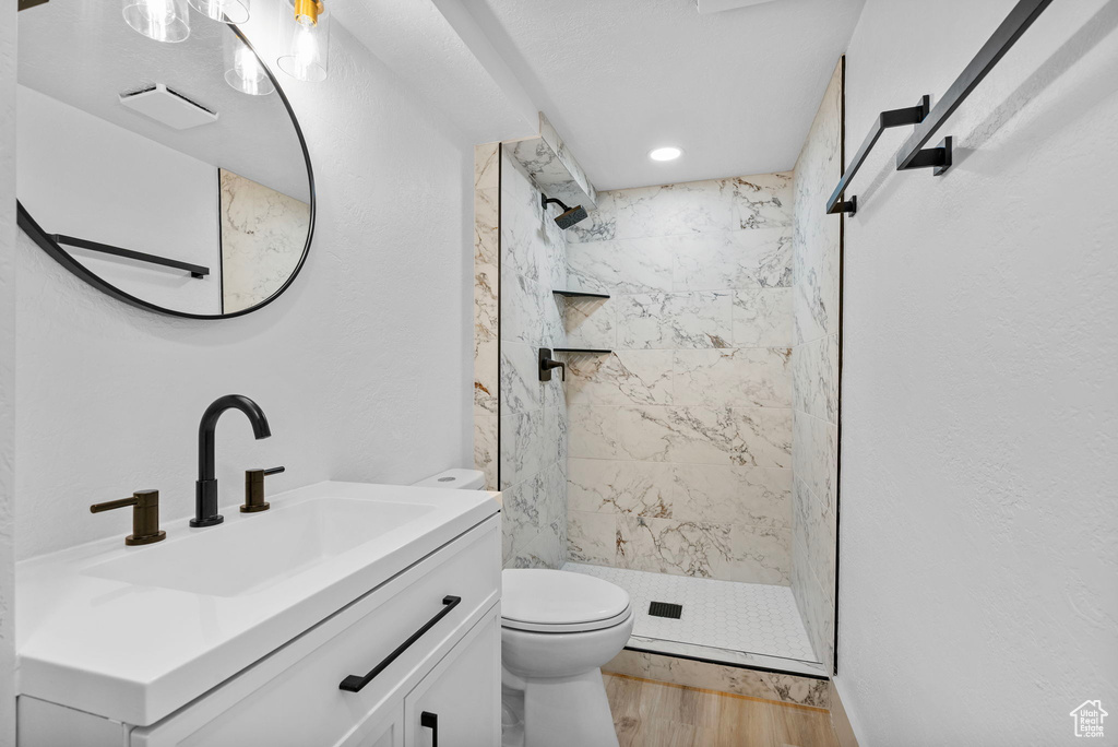 Bathroom featuring a marble finish shower, wood finished floors, and vanity
