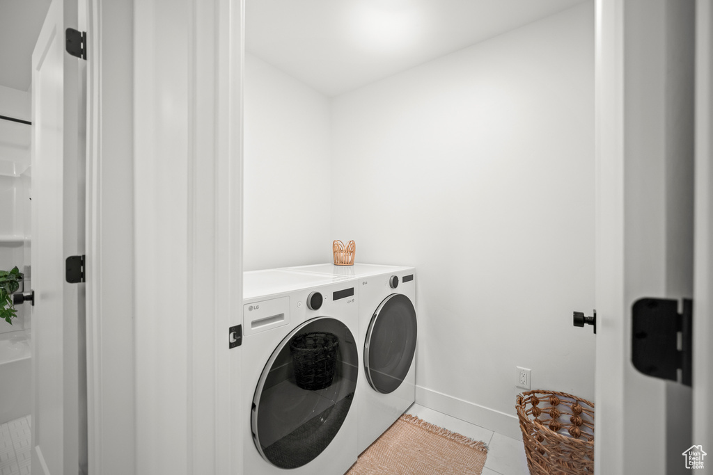 Laundry room with washer and clothes dryer and light tile patterned floors
