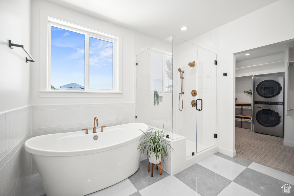 Bathroom featuring stacked washer / drying machine, a shower stall, a freestanding bath, and recessed lighting