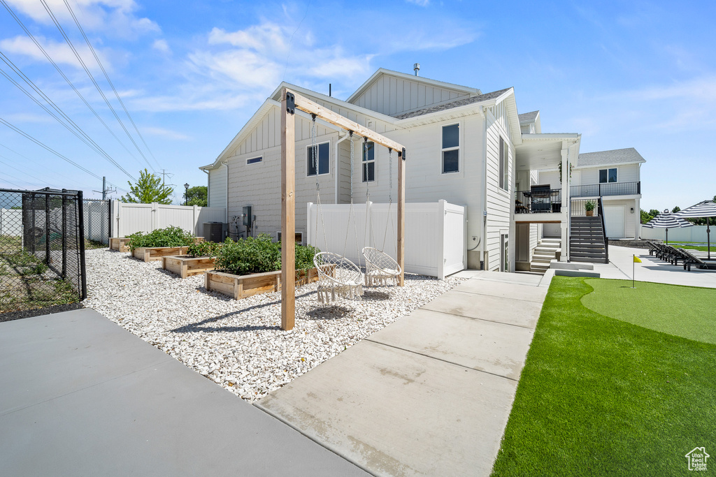 Rear view of house featuring board and batten siding, stairs, a putting area, a vegetable garden, and a gate