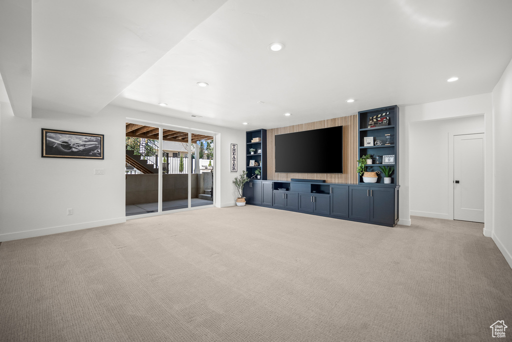 Unfurnished living room with light carpet, stairway, and recessed lighting