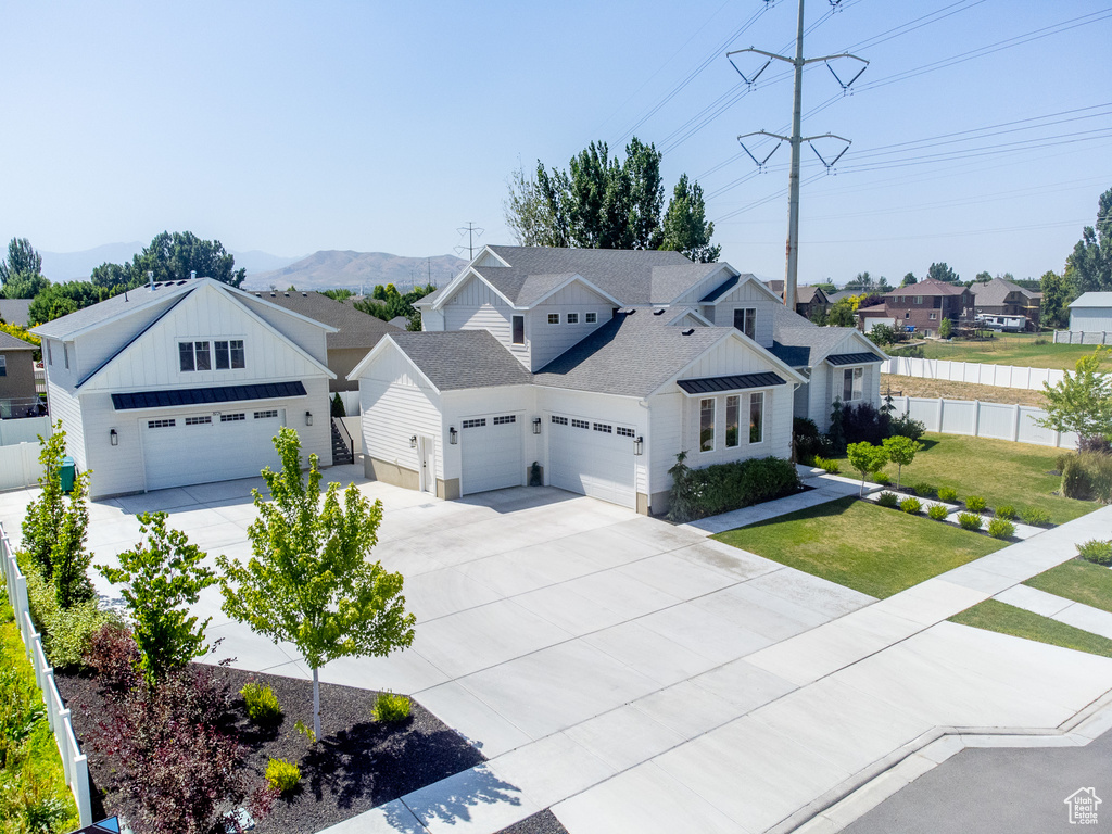 Modern farmhouse featuring driveway, a residential view, an attached garage, board and batten siding, and a mountain view