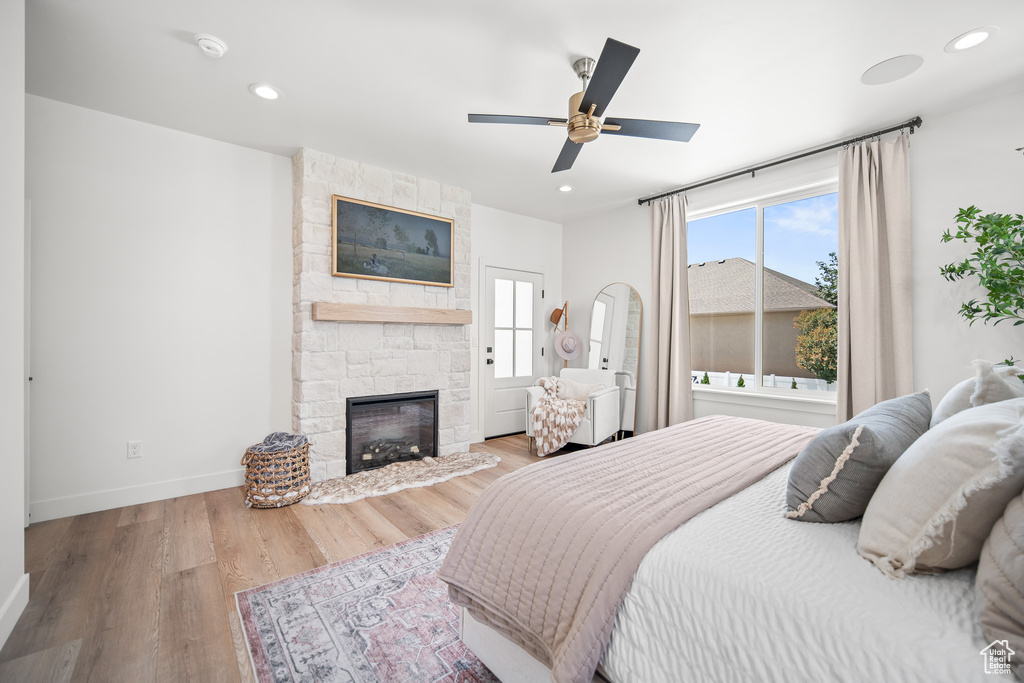 Bedroom with wood finished floors, a fireplace, recessed lighting, and a ceiling fan