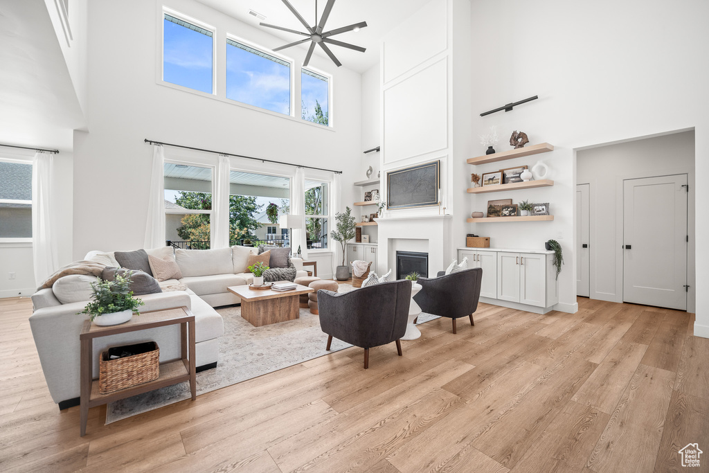 Living room with a towering ceiling, light wood-type flooring, and a fireplace
