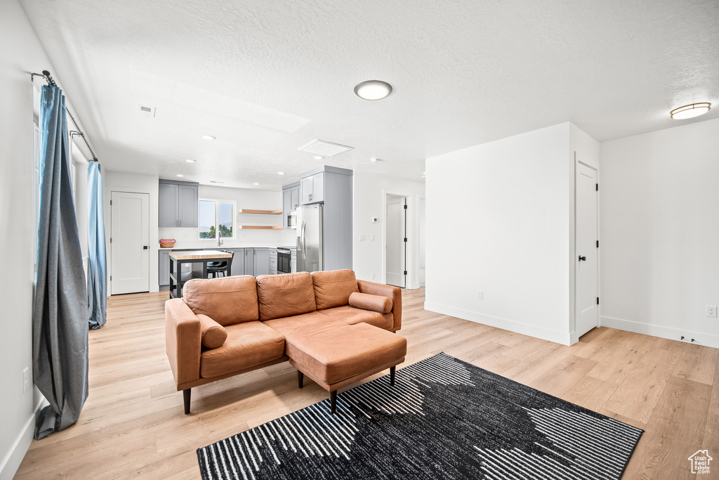 Living area with light wood-type flooring, a textured ceiling, and recessed lighting