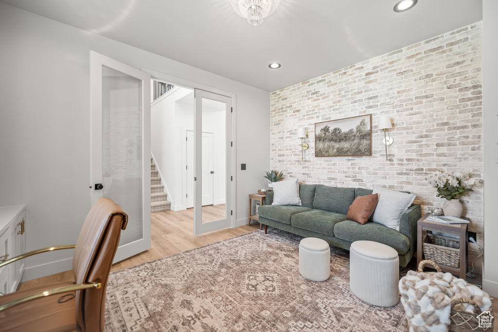 Living room with wood finished floors, brick wall, stairway, recessed lighting, and an accent wall