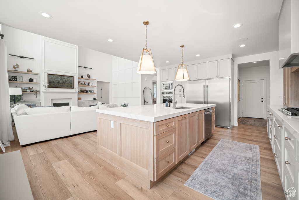 Kitchen featuring built in appliances, recessed lighting, a fireplace, light wood-style floors, and light brown cabinetry