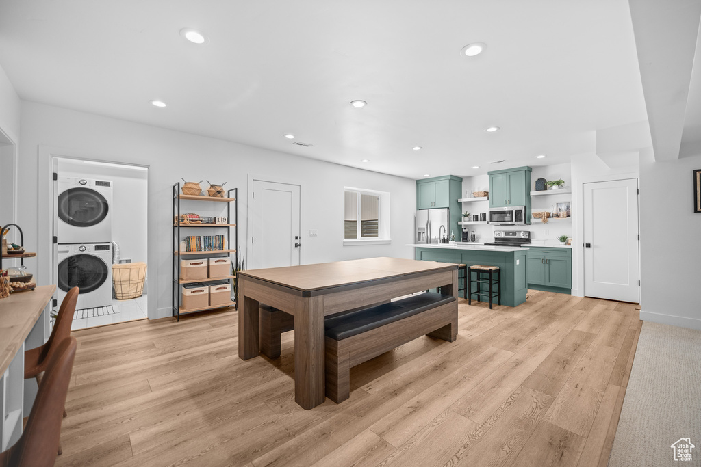 Recreation room with stacked washing machine and dryer, light wood-type flooring, and recessed lighting