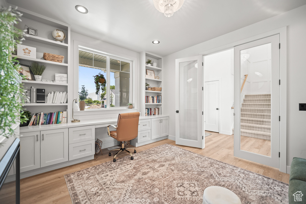 Office with built in desk, light wood-type flooring, and recessed lighting