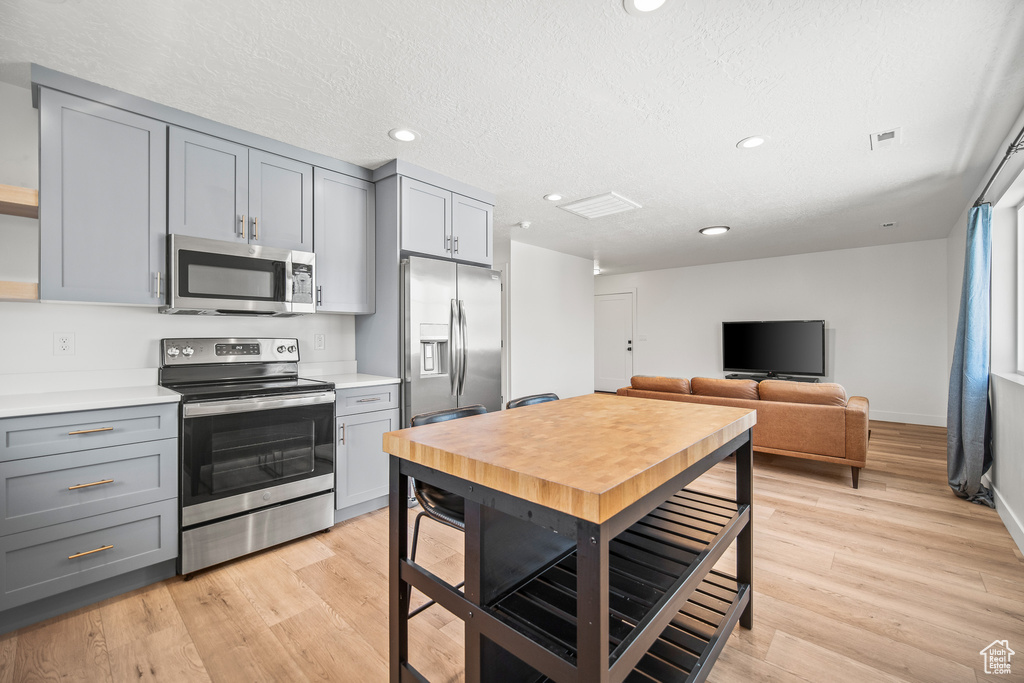 Kitchen with appliances with stainless steel finishes, gray cabinets, light countertops, recessed lighting, and light wood-type flooring