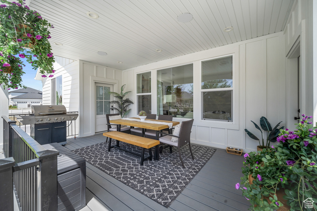 Wooden terrace featuring outdoor dining space and grilling area