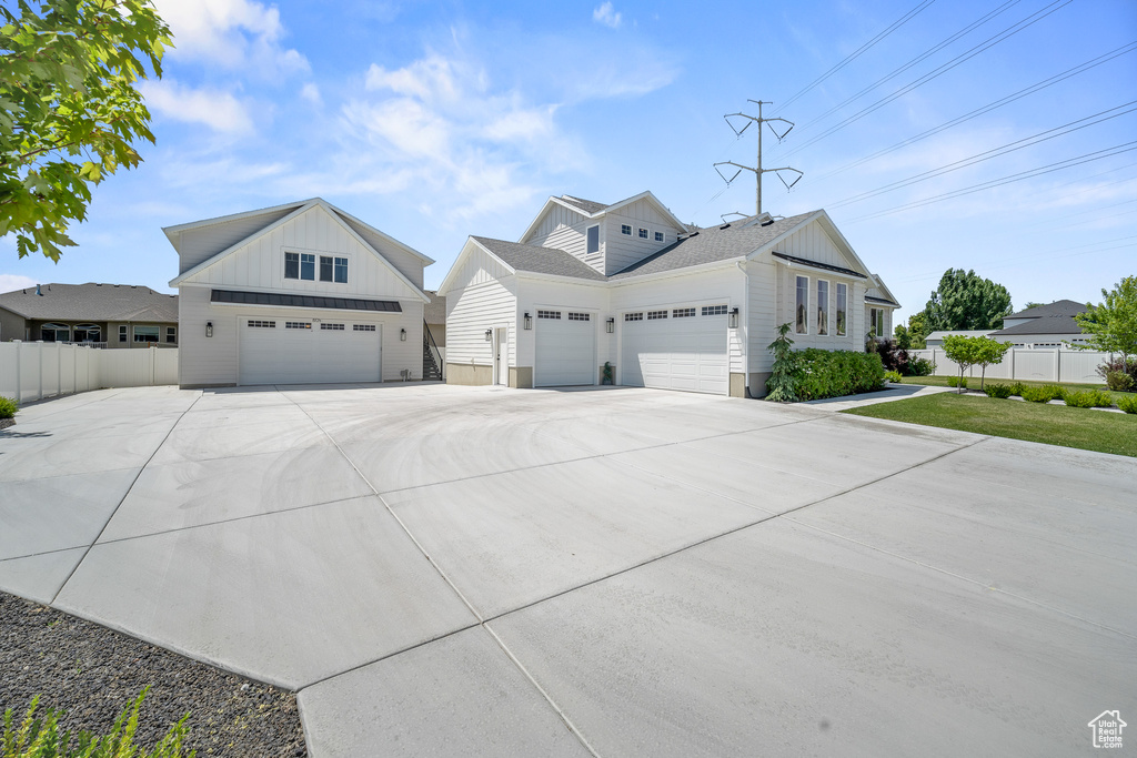 View of front facade with board and batten siding, driveway, and a garage