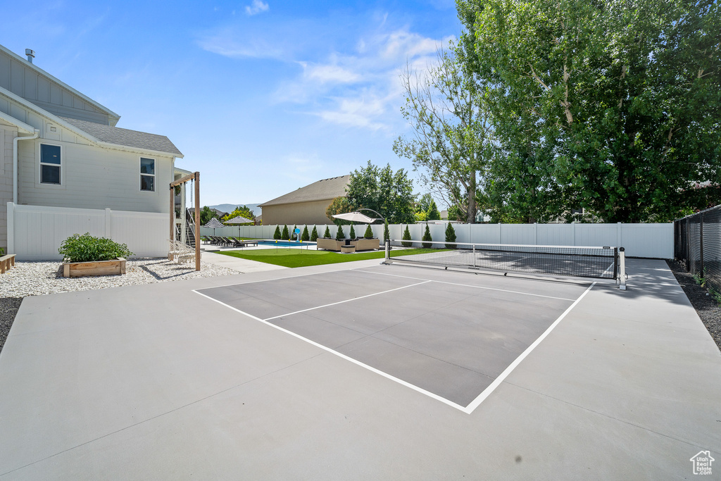 View of tennis court featuring a pool and a patio area