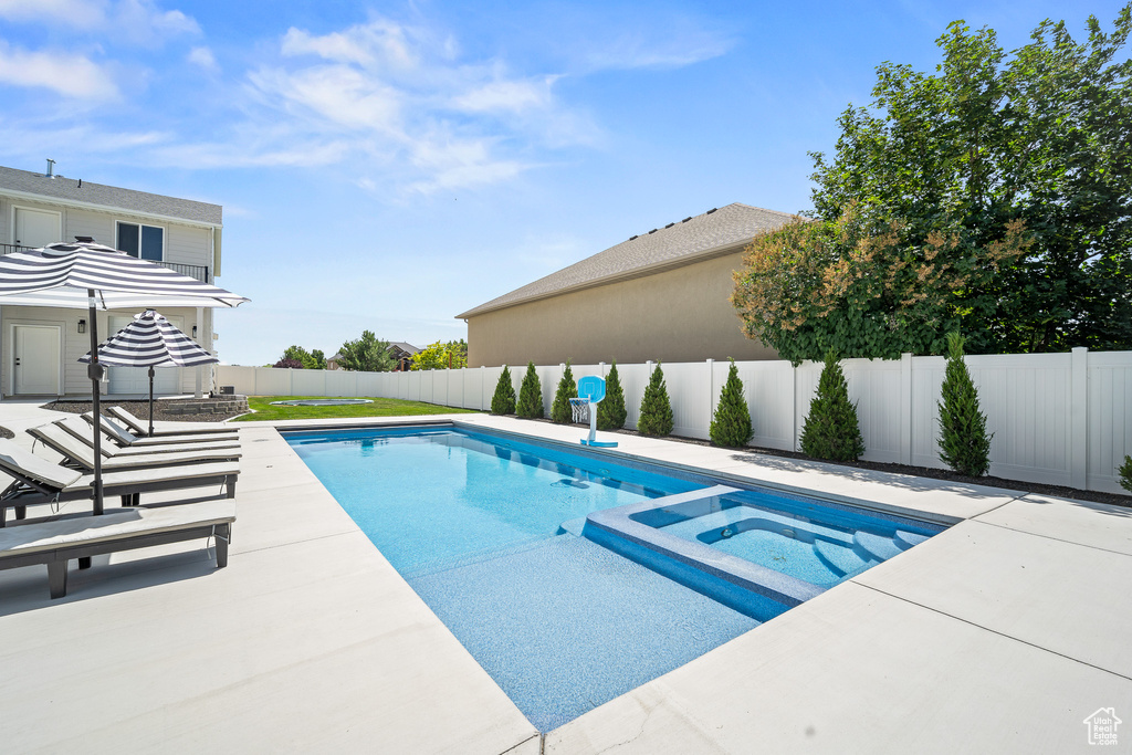 View of pool featuring a fenced backyard, a patio, and a pool with connected hot tub