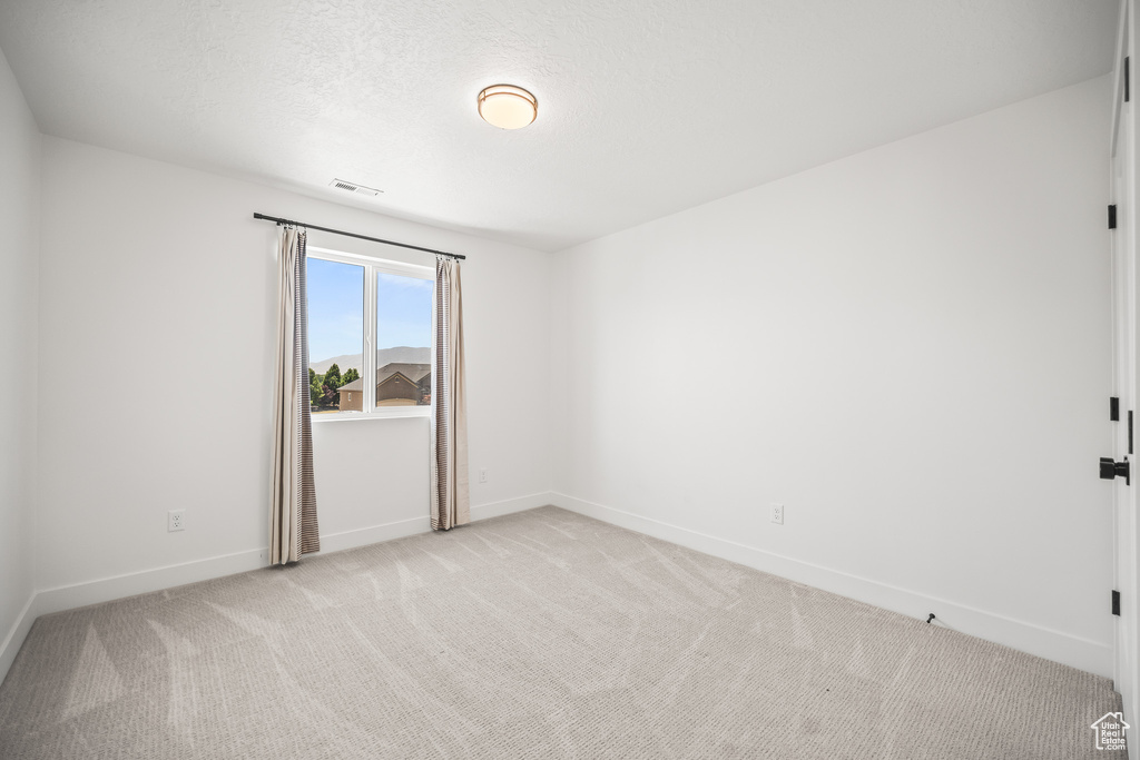 Spare room featuring light colored carpet and baseboards