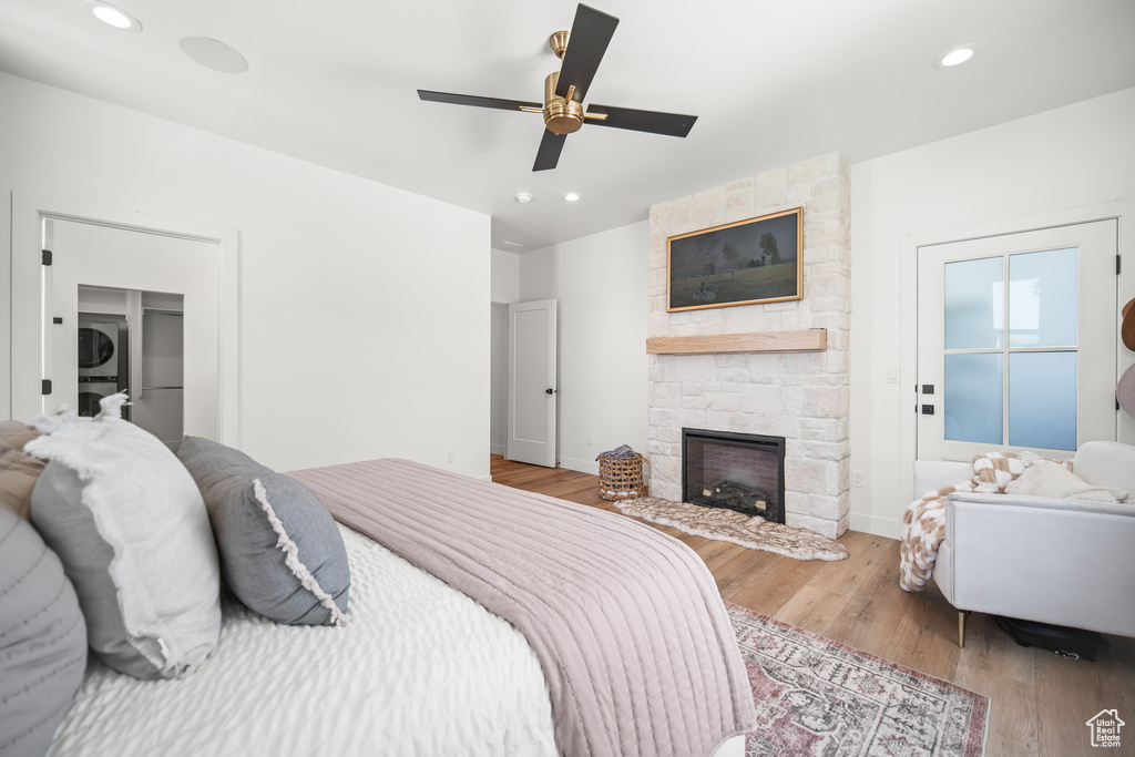 Bedroom with wood finished floors, a stone fireplace, recessed lighting, and a ceiling fan