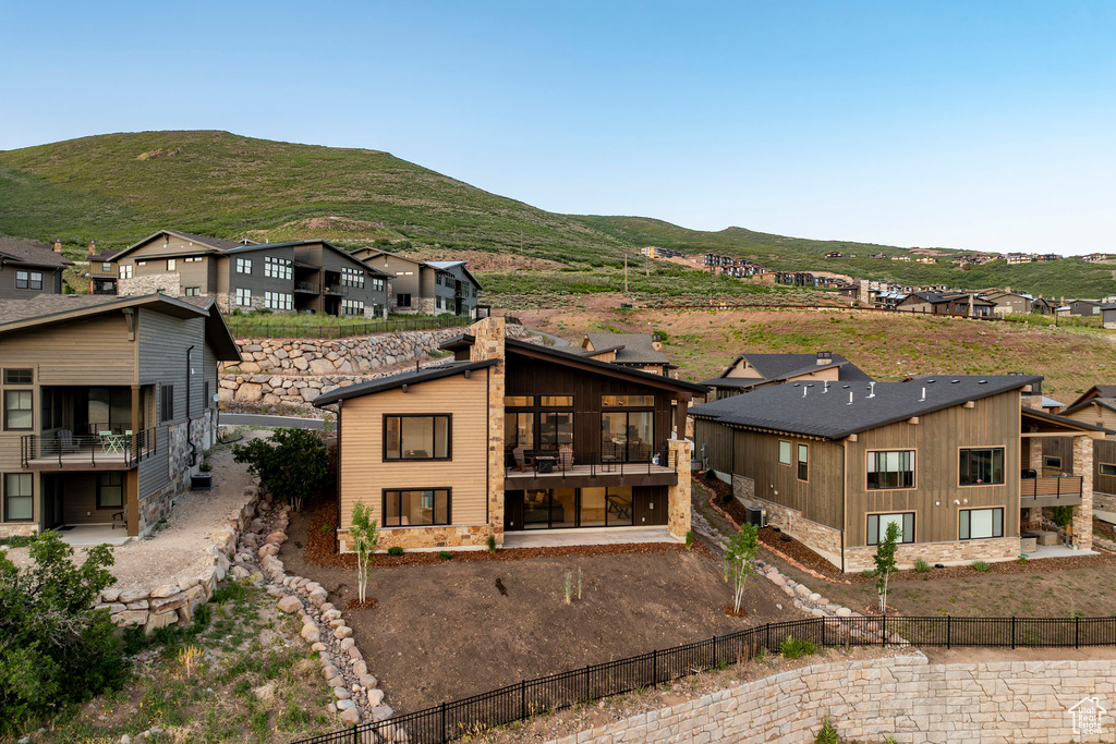 Back of property featuring a fenced backyard, a mountain view, a residential view, a sunroom, and a chimney