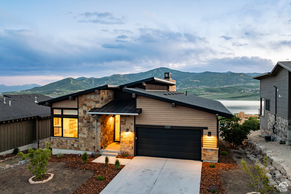 Modern home with stone siding, a mountain view, and a chimney