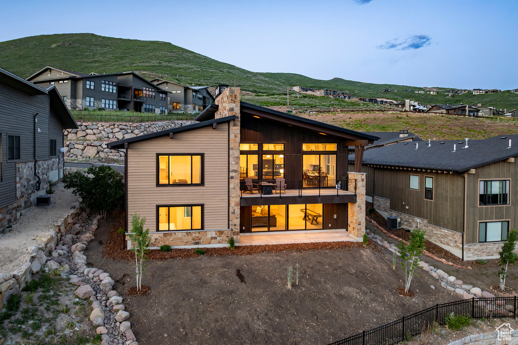 Back of house featuring a chimney, a mountain view, stone siding, and a balcony