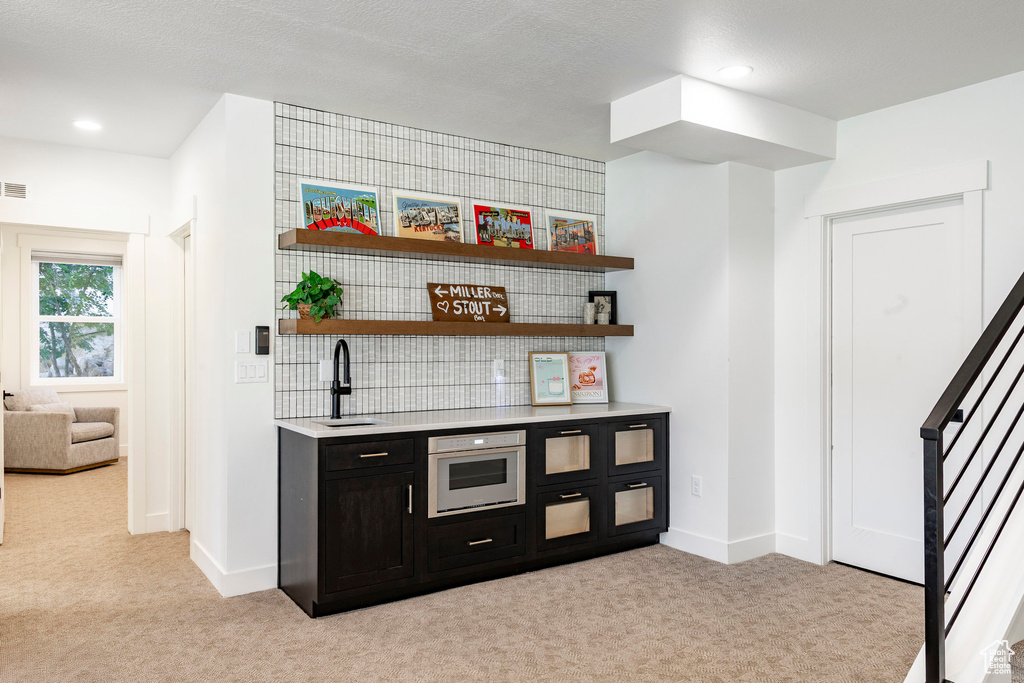 Indoor wet bar featuring light colored carpet, stairway, white oven, and recessed lighting