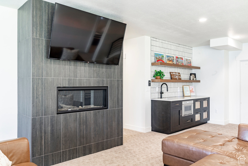 Living area featuring light carpet, a glass covered fireplace, bar area, and recessed lighting