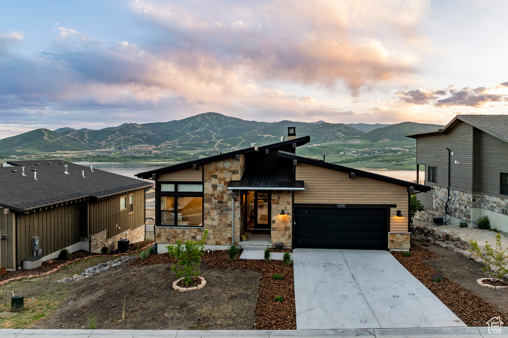 Contemporary house featuring stone siding, a mountain view, a garage, and driveway