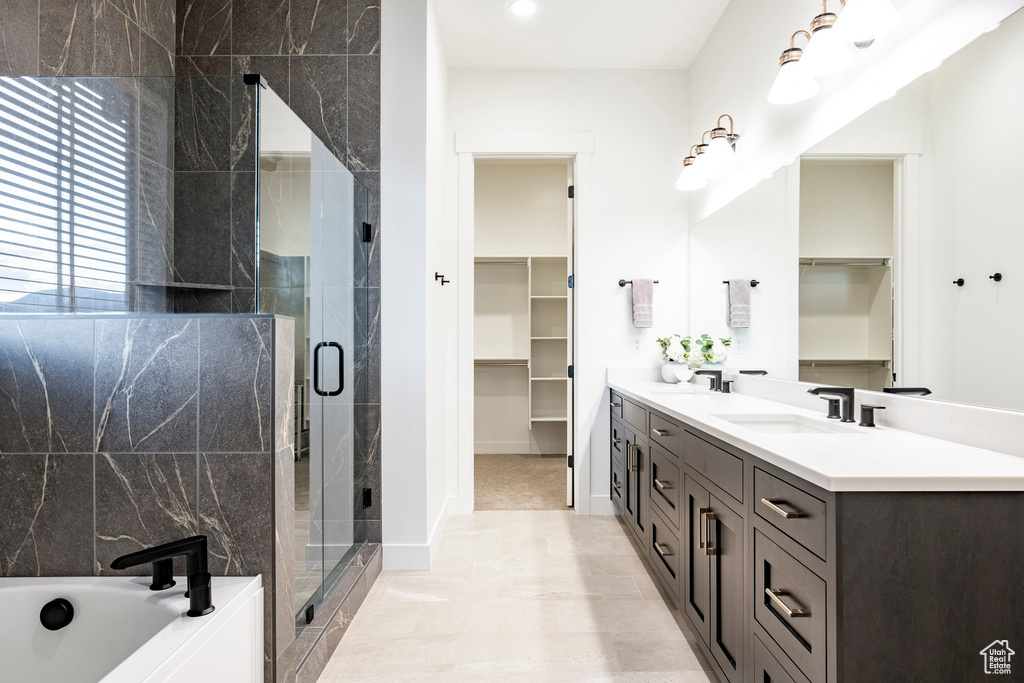 Full bath featuring double vanity, a walk in closet, a stall shower, and a bath