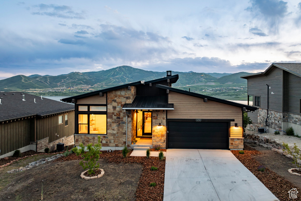 Contemporary house featuring stone siding, a mountain view, a garage, and concrete driveway
